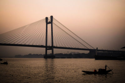 Silhouette of suspension bridge in city