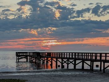 Pier over sea against sky during sunset