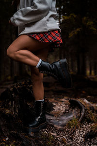 Low section of woman standing on ground in forest