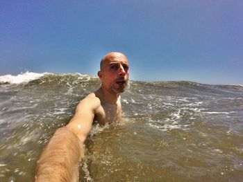 Portrait of shirtless man in sea against sky