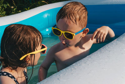 Happy and funny children playing in the pool. friends spend summer leisure together on a hot day