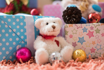 Teddy bear amidst christmas decors and presents on rug at home