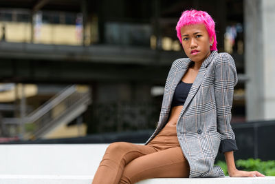 Woman looking away while sitting outdoors