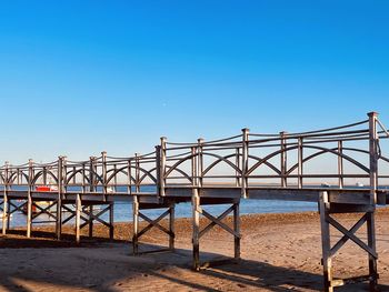 Bridge over sea against clear blue sky