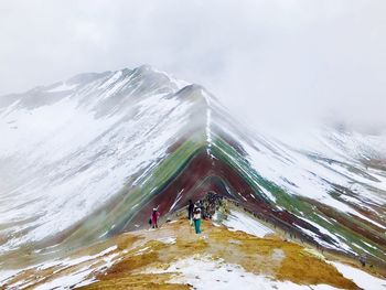 People on snowcapped mountain against sky