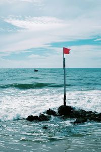 Scenic view of red flag against sea and sky