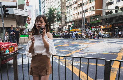 Young woman using smart phone on city street