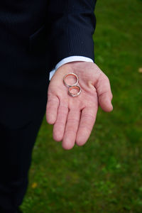 Midsection of a man holding cigarette on field