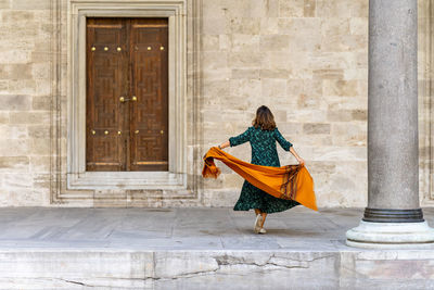 Rear view of woman walking against building