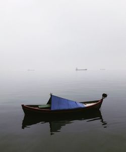 Boat moored on lake against sky