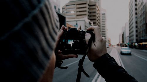 Midsection of man photographing on city street