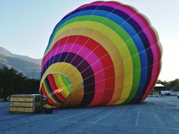 Multi colored hot air balloon on land against clear sky