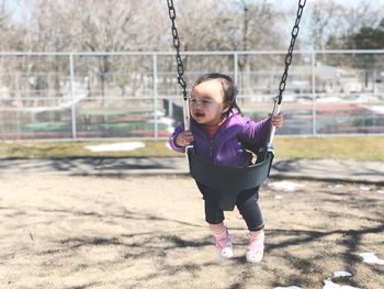 Full length of a girl standing on swing at playground