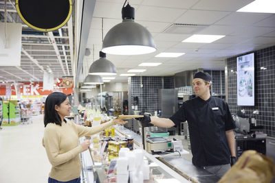 Female customer in supermarket buying products at deli counter