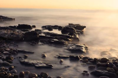 Aerial view of sea and rocks at sunset