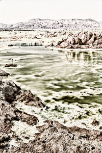 Scenic view of rocky shore against sky during winter