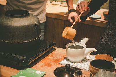 Midsection of woman making tea in kitchen