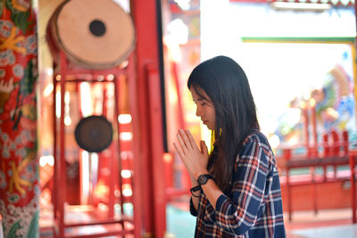 Side view of woman praying at temple