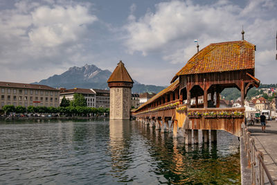 Bridge over river by buildings against sky