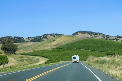 Road amidst landscape against clear blue sky