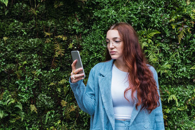 Young business woman looking at smart phone while writing a message, empty space for text