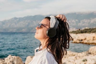 Portrait of woman wearing sunglasses standing against sea