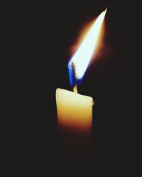 Close-up of lit candle in darkroom