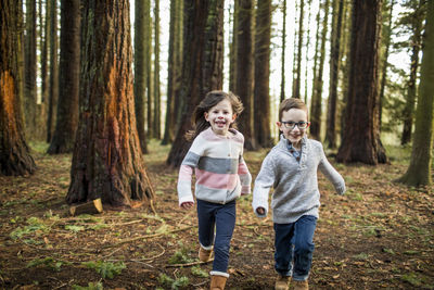 Boy and girl running through trees in the park.