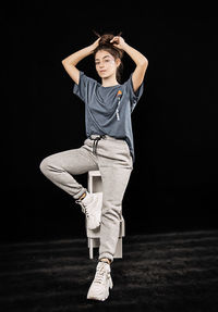 Full length of woman standing against black background