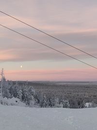 Scenic view of snowy field against sky during sunset