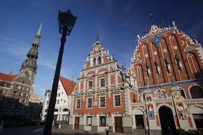 Low angle view of church by walkway against blue sky during sunny day