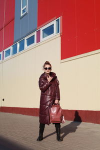 Full length of woman standing against red wall