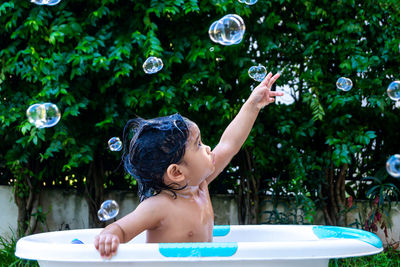 Full length of shirtless boy with bubbles in water