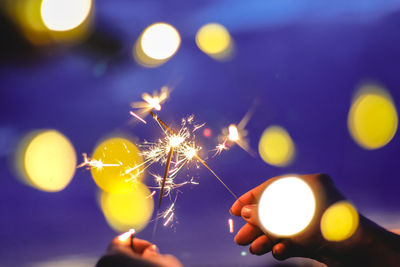 Blurred motion of person hands holding sparkler at night