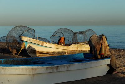 Abandoned boat moored on shore against sky