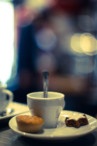 Close-up of coffee cup with cupcakes and cookie on table