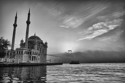 View of buildings at waterfront against cloudy sky