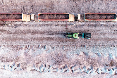 Aerial view above mineral ore quarry with railway wagons and bowser spraying to dampen down dust