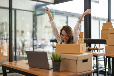 Portrait of woman using phone while sitting on table