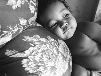 Close-up of shirtless baby boy lying on pregnant mother belly