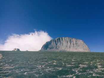 Scenic view of field and mountain against blue sky