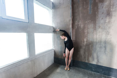 Full length of woman standing against window