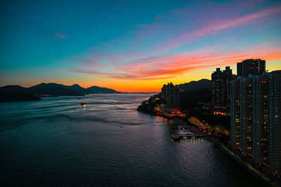 Scenic view of sea and buildings against sky at sunset