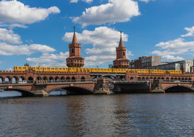 Arch bridge over river against cloudy sky