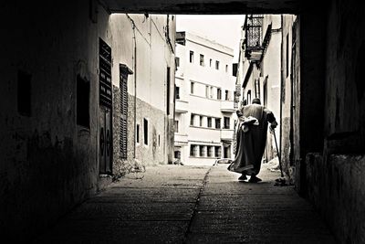 Rear view of woman walking along buildings