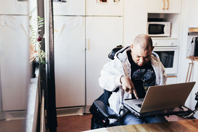 Disabled male using laptop while sitting on wheelchair at recording studio