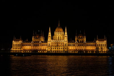 Illuminated hungarian parliament building by river at night