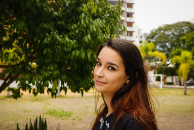 Portrait of smiling woman standing by tree