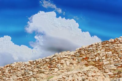 Low angle view of rocky mountains against blue sky