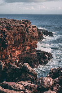 Rock formation by sea against sky